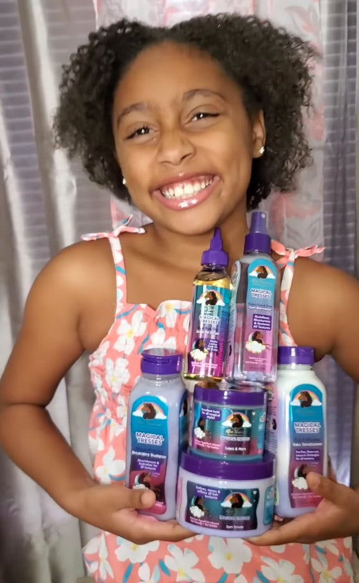A child holding Afro Unicorn products while smiling.